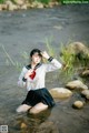 A woman in a white shirt and black skirt sitting in a river.