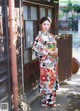 A woman in a kimono standing in front of a building.