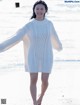 A woman in a white sweater is walking on the beach.