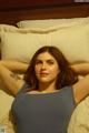 A woman laying on a bed with her arms behind her head.
