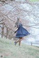 A woman in a blue dress is standing in the grass.