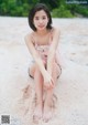 A woman sitting on a sandy beach with her legs crossed.