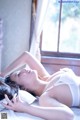 A woman laying on a bed in a white lingerie.